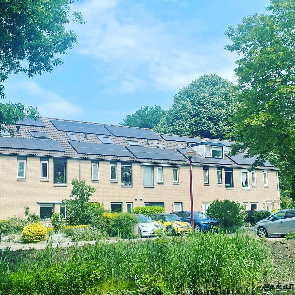 Complete rij woningen met zonnepanelen op meerdere dakvlakken